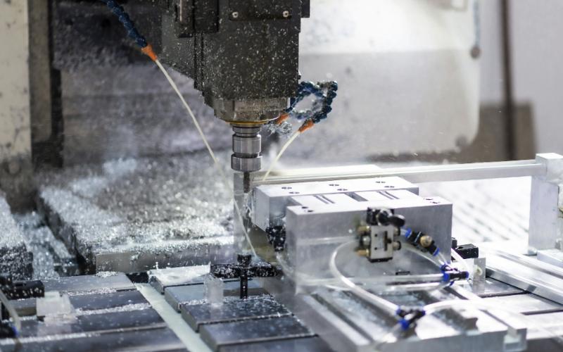 A vertical machining centre cutting an aluminium part under flood coolant.
